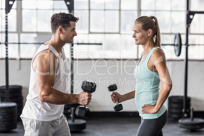 couple exercising with dumbbells in gym