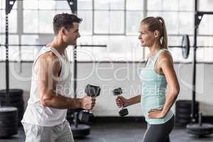 couple exercising with dumbbells in gym