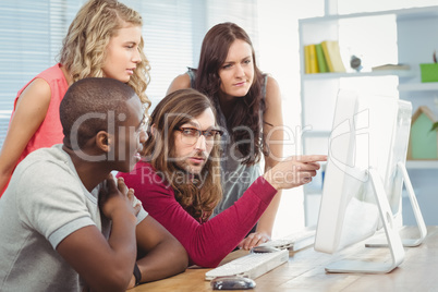 Man pointing at computer while working with coworkers