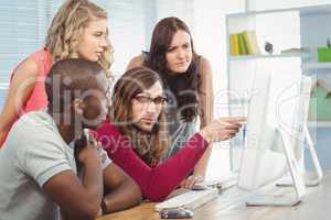 Man pointing at computer while working with coworkers