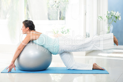 Pregnant woman exercising with ball on mat