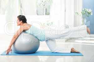 Pregnant woman exercising with ball on mat