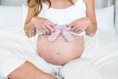 Midsection of woman with baby shoes on abdomen