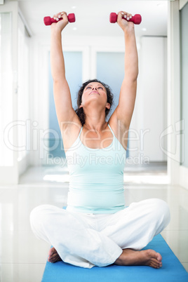 Pregnant woman exercising with dumbbells while sitting on exerci