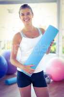 Portrait of woman smiling while holding yoga mat