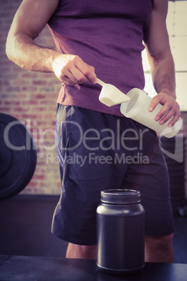 Midsection of man putting supplement into bottle