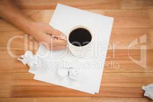 Man holding black coffee cup on paper at desk