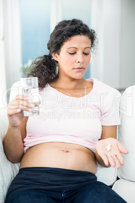 Pregnant woman taking pill at home