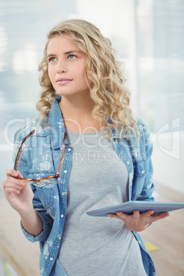 Woman holding eyeglasses and digital tablet