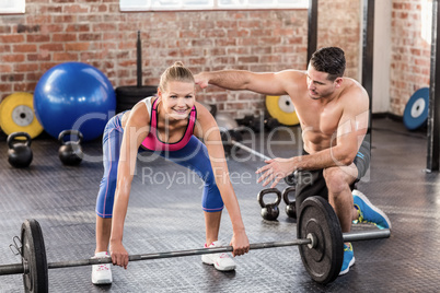 Woman lifting barbell with her trainer
