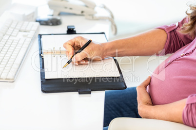 Midsection of businesswoman writing agenda