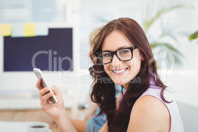 Portrait of smiling woman wearing eyeglasses while holding smart