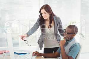 Businesswoman holding eyeglasses while looking at computer