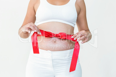 Pregnant woman opening red ribbon around her bump