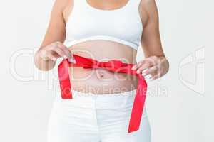 Pregnant woman opening red ribbon around her bump