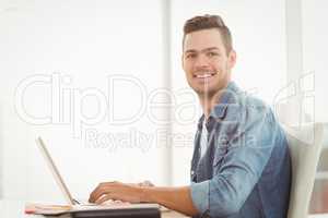 Portrait of smiling young man working on laptop