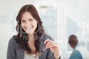 Portrait of happy businesswoman holding eyeglasses