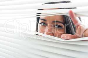 Woman peeking through some window blinds