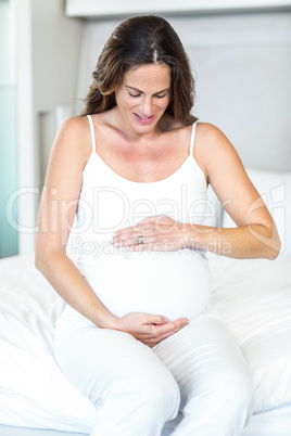 Pregnant woman sitting on bed