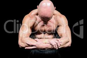 Bodybuilder flexing muscles while looking down