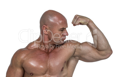 Muscular man looking at bicep