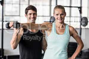 Male trainer helping woman with the dumbbells