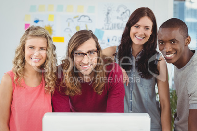 Portrait of smiling business team standing at computer desk