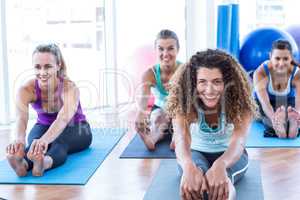 Portrait of woman doing forward bend pose with friends