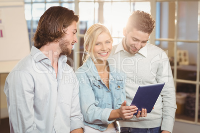 Businesswoman holding laptop standing with male colleagues