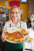 Happy female worker serving pastries in plate