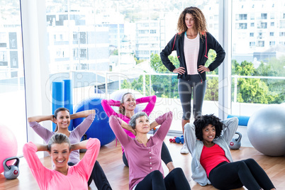 Young female trainer assisting women sit ups