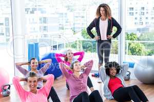 Young female trainer assisting women sit ups
