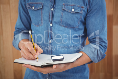 Mid section of man writing with pencil on book