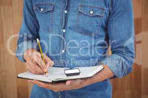 Mid section of man writing with pencil on book