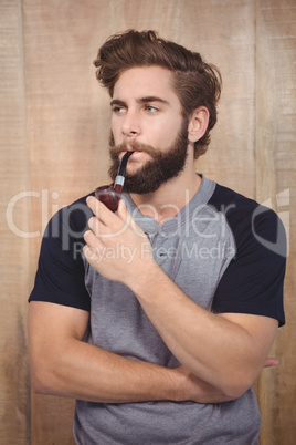 Confident hipster smoking pipe