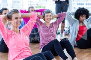 Happy women doing sit ups on hardwood floor