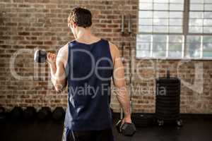 Rear view of man lifting dumbbells