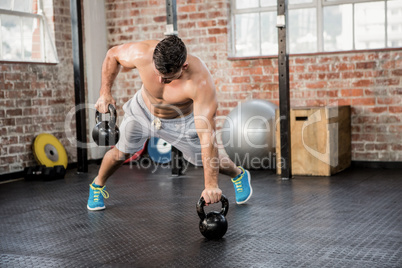 Shirtless man lifting kettlebell