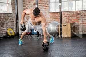 Shirtless man lifting kettlebell