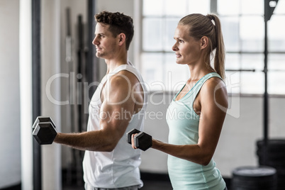 couple exercising with dumbbells in gym