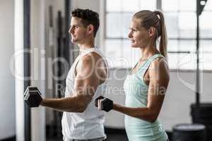 couple exercising with dumbbells in gym