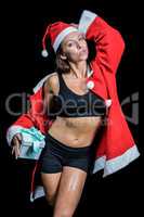 Portrait of sexy athlete in Christmas costume while holding pres