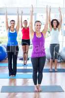 Happy women in fitness studio with arms raised