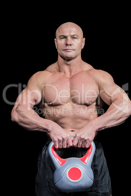 Portrait of muscular fit man lifting kettlebell