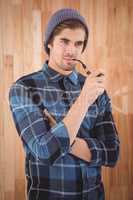 Hipster smoking pipe against wooden wall