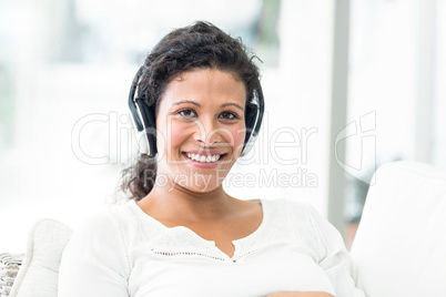 Portrait of happy woman with headphones on sofa