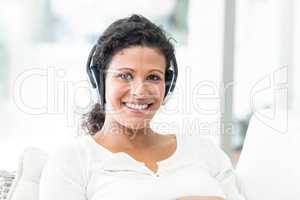Portrait of happy woman with headphones on sofa