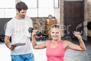 Fit woman lifting dumbbells with trainer