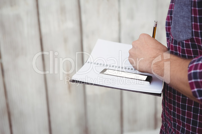 Cropped image of man with smartphone writing on book