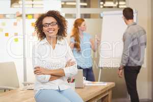 Businesswoman with arm crossed with colleagues in background